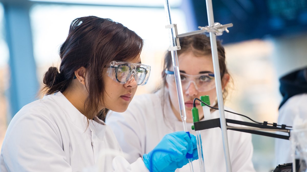 Two students using titration equipment in a lab