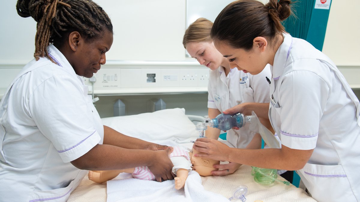 Midwifery students practising CPR on a baby mannequin