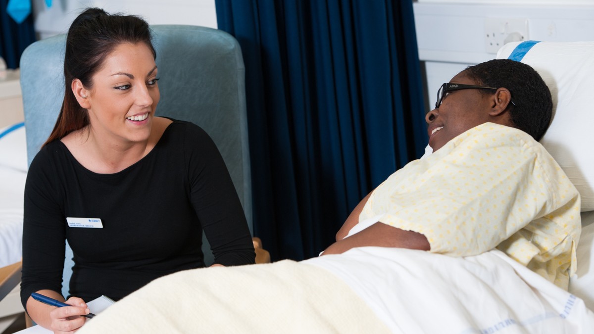 Mental health nursing student speaking to patient in a hospital bed