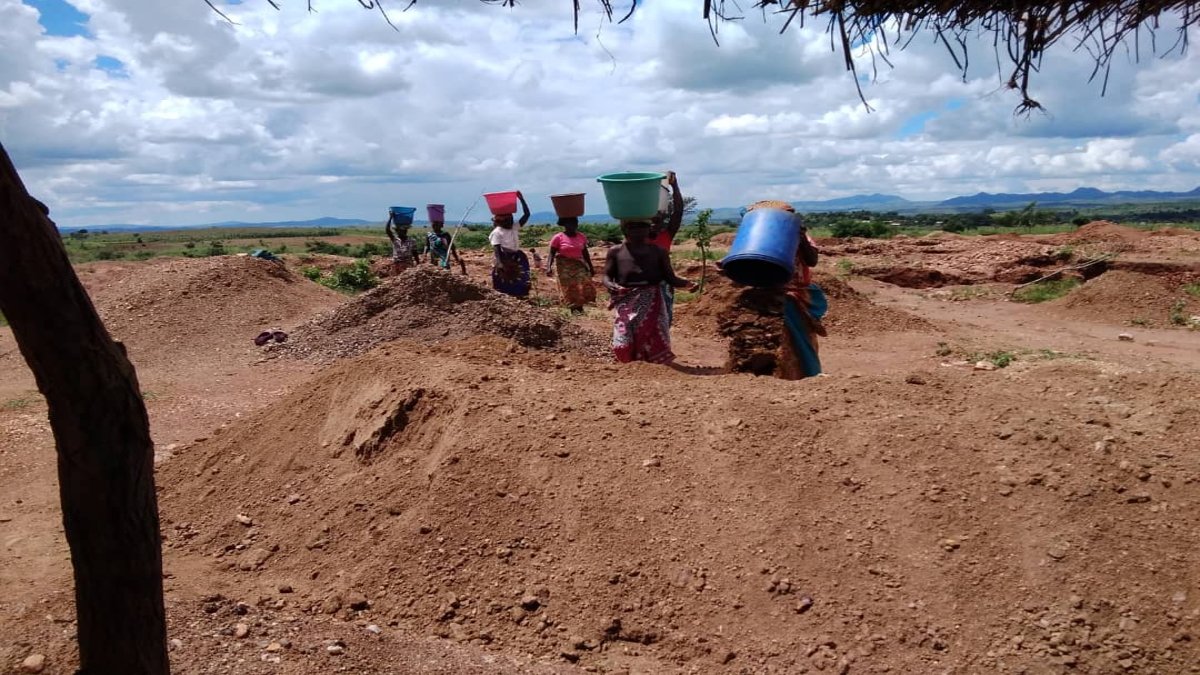A group of women carry buckets through the mining site 