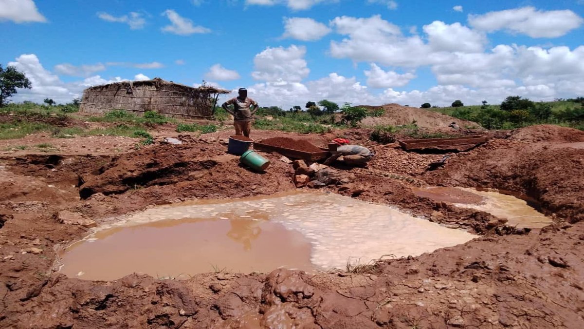 Men panning in the mud near water