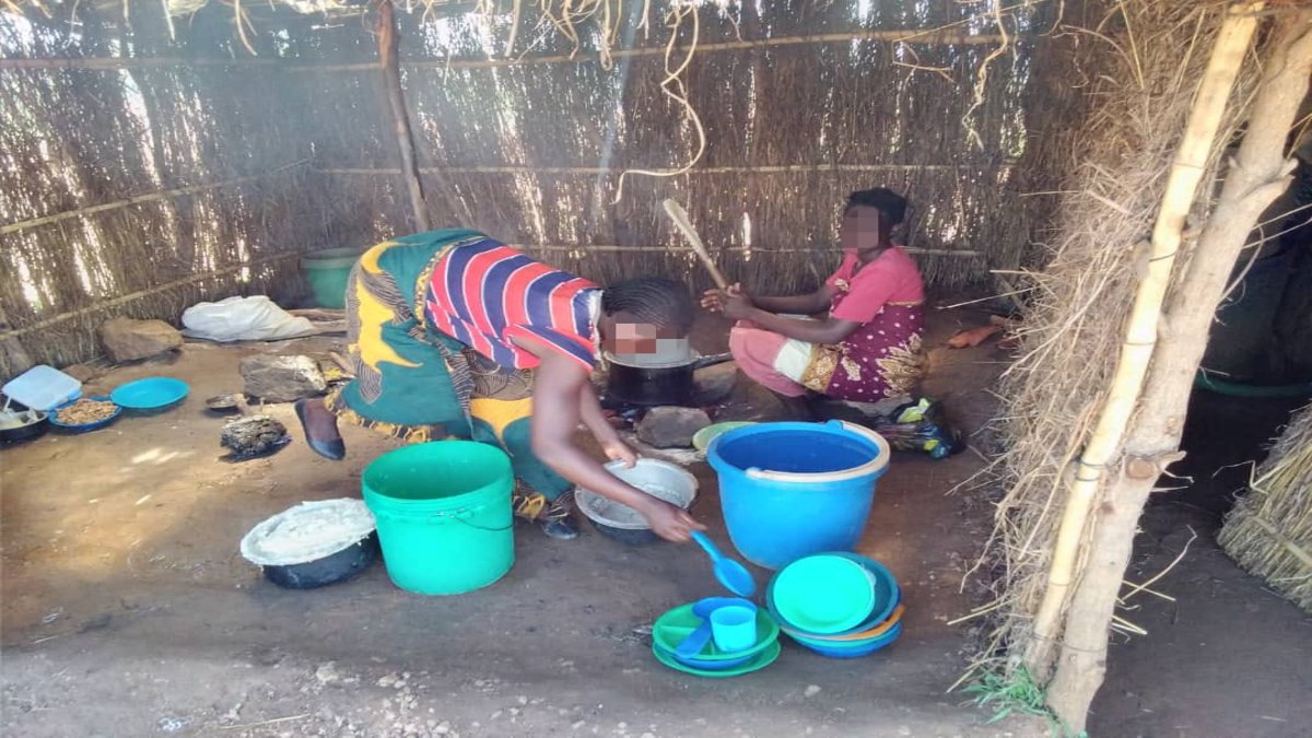 Two women cook together in a sheltered workspace 