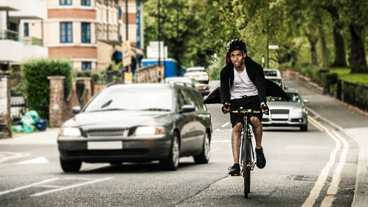 A cyclist on an urban road is overtaken by a car