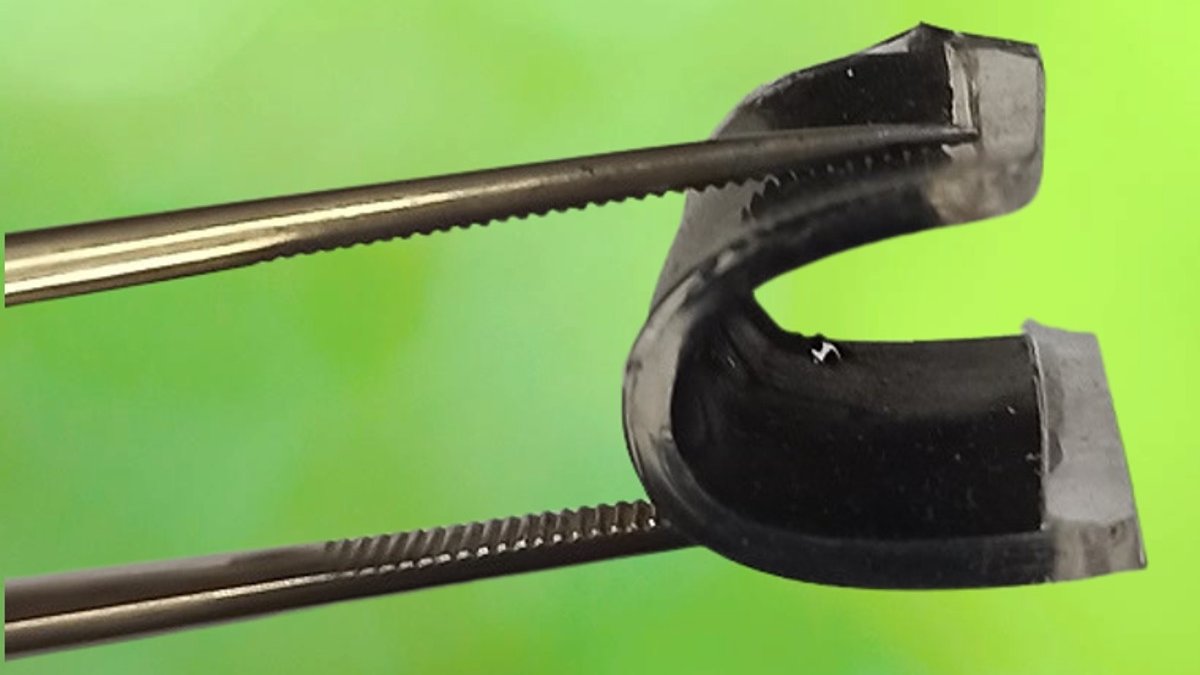 Tongs holding a small, black supercapacitor bent into a U shape