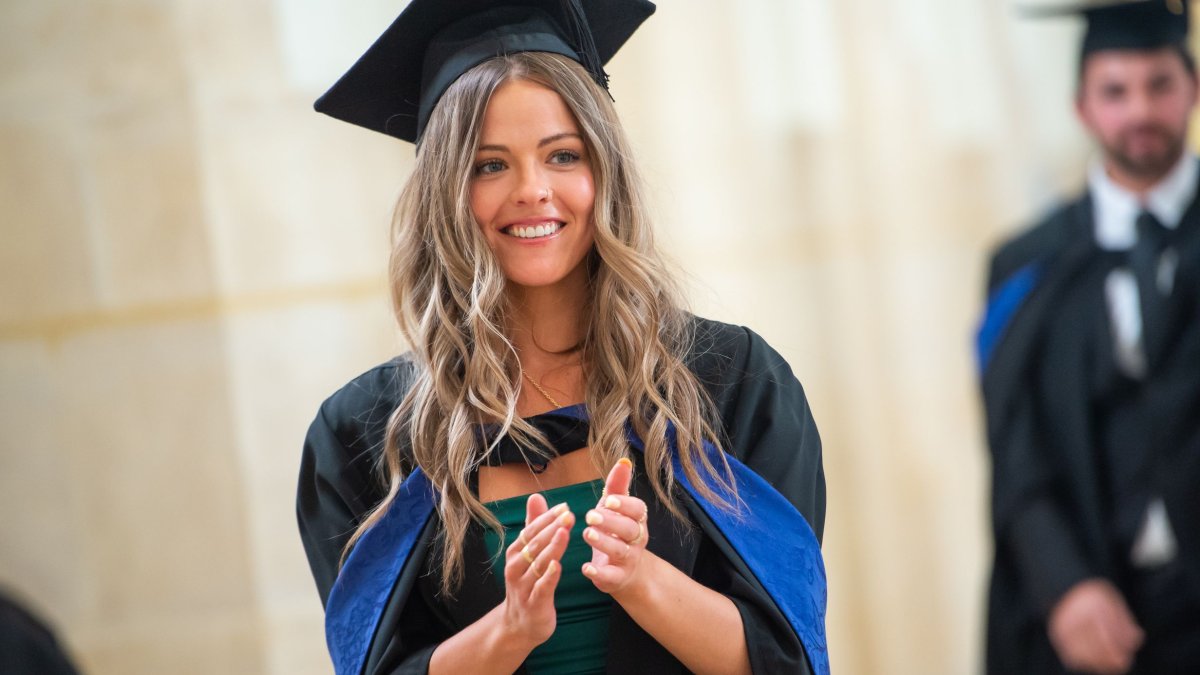 A graduand clapping as they wait to be called onto the stage