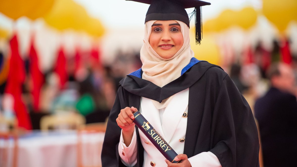 A graduate standing in the reception holding their scroll