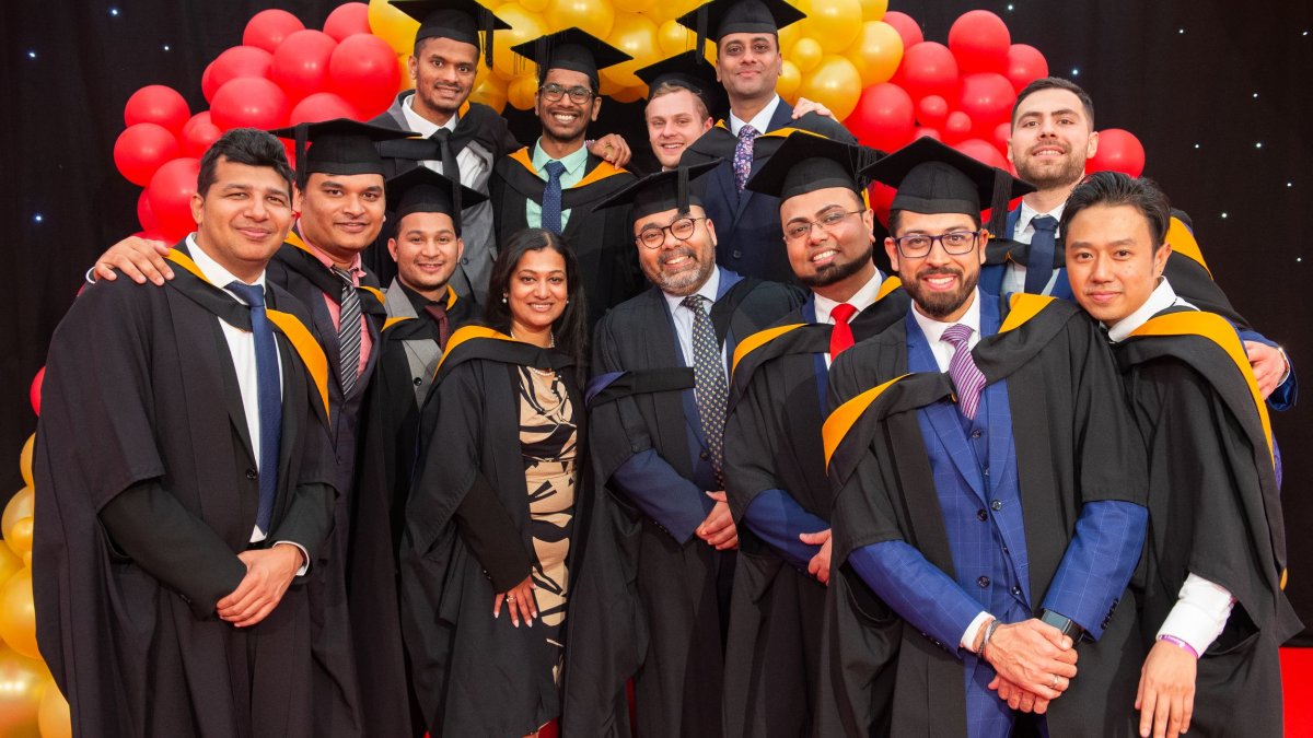 A group of graduates gathering in front of a balloon arch