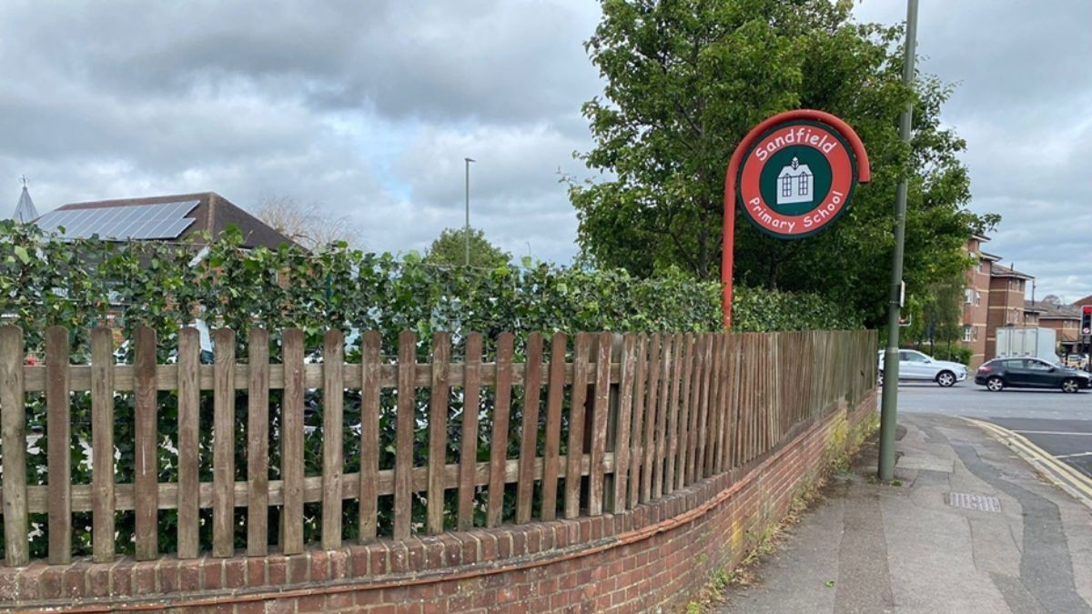 A wooden fence goes round a corner with a hedge behind it