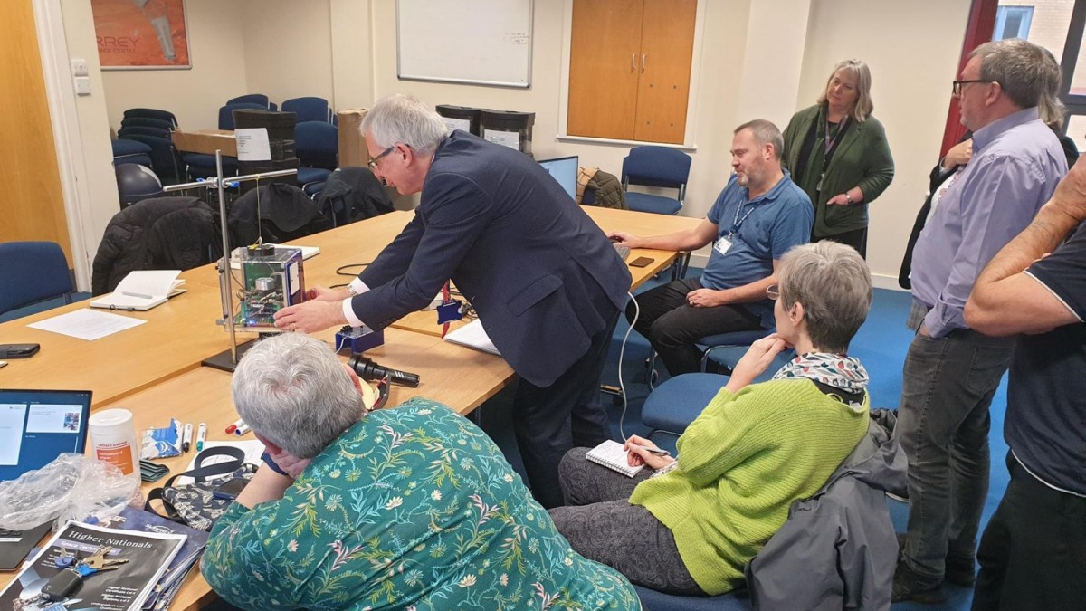 Teachers watch while a professor shows them a teaching satellite