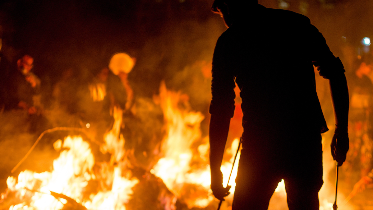 silhouette of a man against a rural fire in India