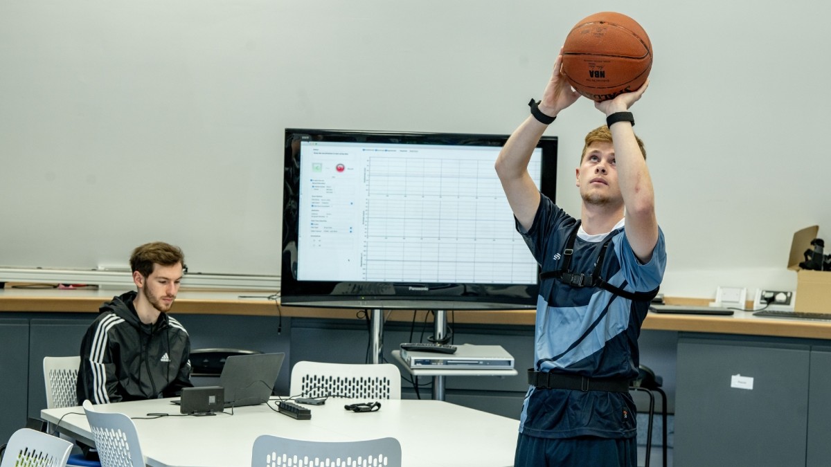 2 students in the Biomedical Engineering study space, 1 student is playing with a basketball