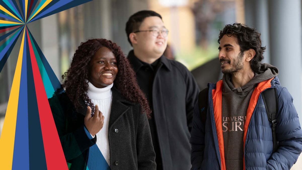 Three smiling students walking through campus