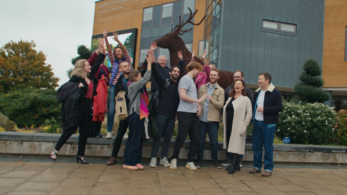 CDT researchers jumping and smiling outside, near Surrey stag statue