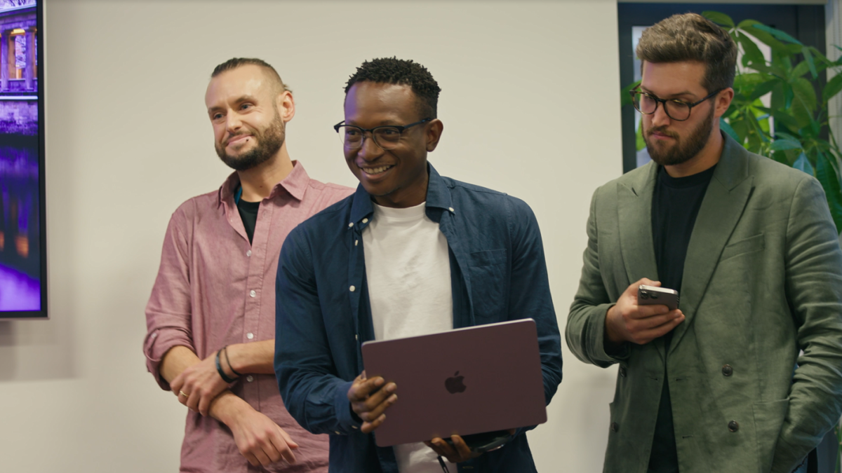 three CDT researchers smiling and looking at laptop