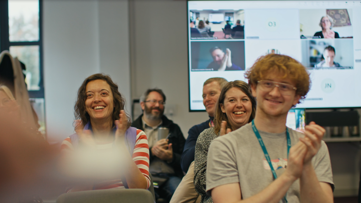 CDT researchers clapping with screen behind them