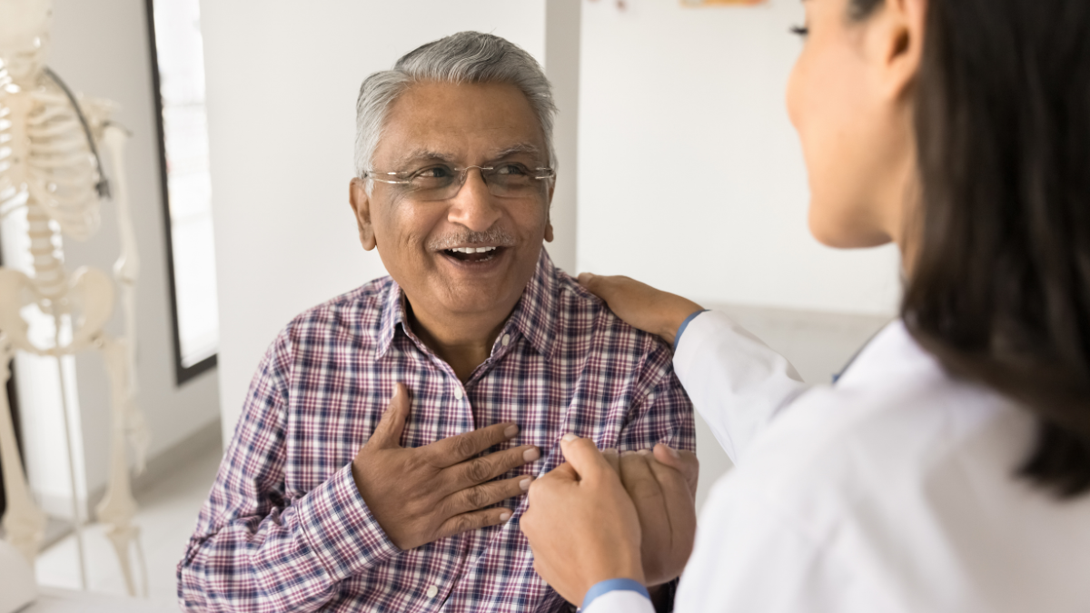 Young doctor woman calming senior Indian patient, holding mans hand, touching shoulder with comfort, support, compassion, telling good news about health, heart work