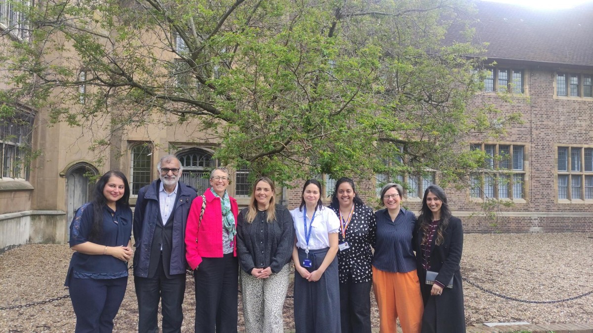 A group of men and women stand in front of a building smiling at the camera.