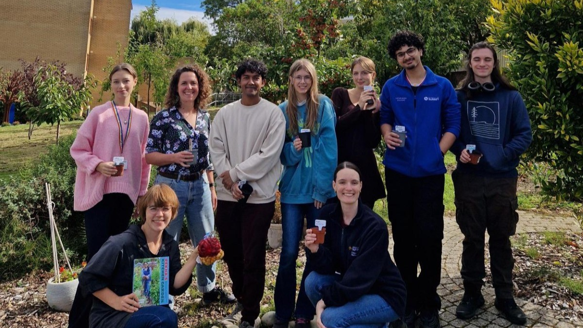 Staff and students pose at the community garden with pots (2026)