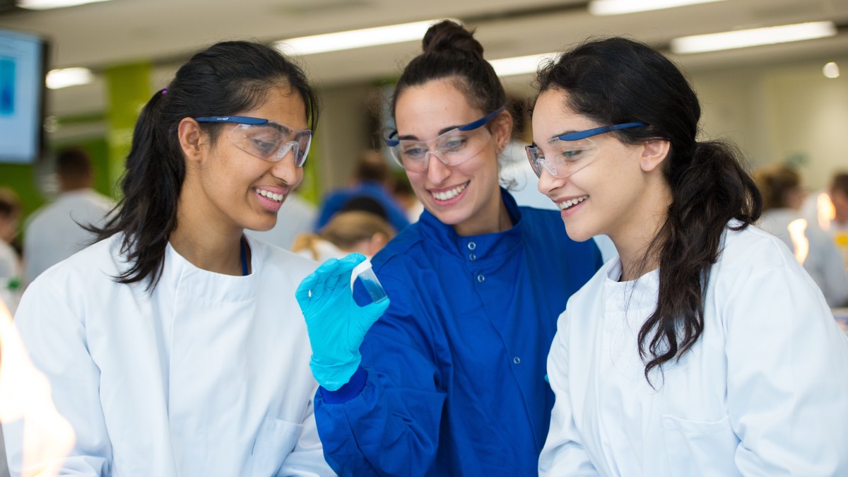 A teacher examines a sample in the lab with students.