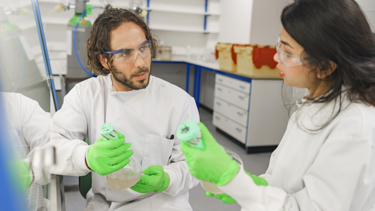 Two biotechnology students discuss a sample in the lab.