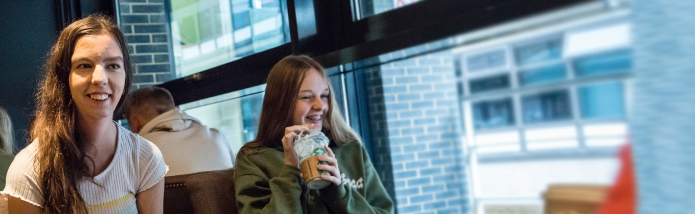 Two students in Starbucks smiling
